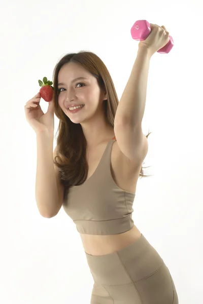 Pretty asian woman with dumbbell and strawberry on white background. — Stock Photo, Image