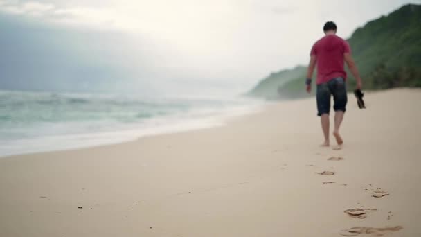 Killen som lämnar fotspår på stranden — Stockvideo