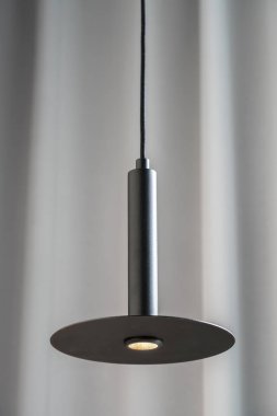 Gri perde arka plan üzerinde asılı siyah metalik lamba