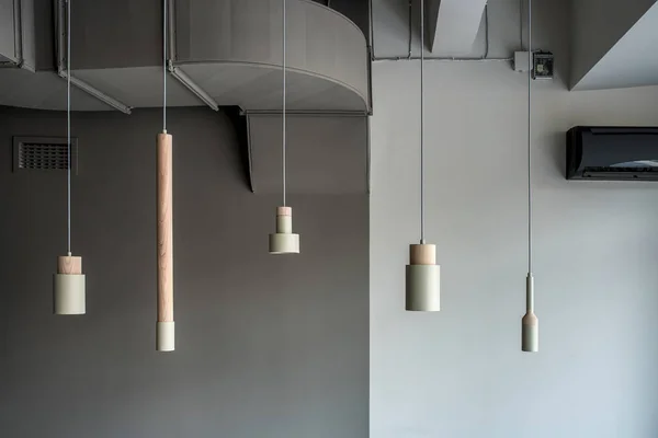 Different metallic-wooden lamps hanging on gray wall background