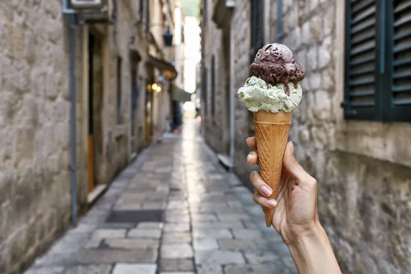 Női kéz a waffle kúp, a régi utcai háttérb fagylalttal — Stock Fotó