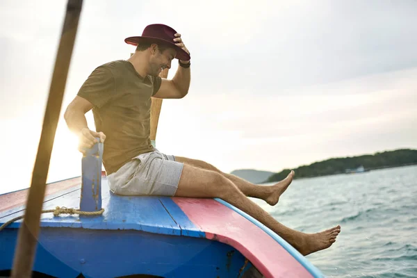 Homem alegre com restolho está navegando em barco colorido — Fotografia de Stock