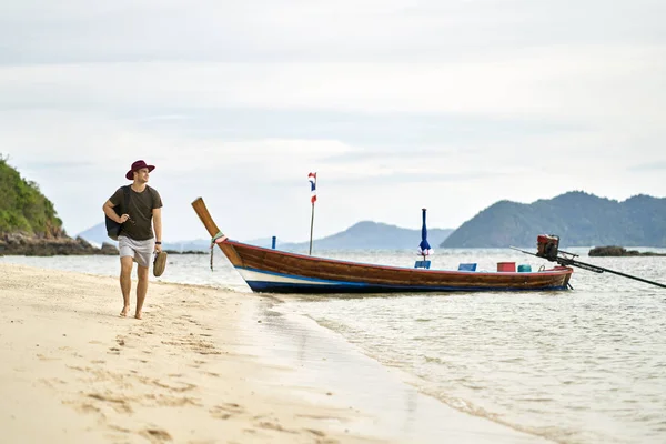 Barfota man med skäggstubb och ryggsäck går på sand beach — Stockfoto