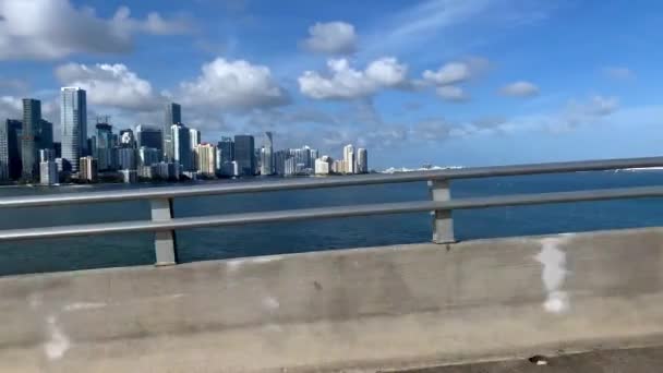 在水堤上的雄伟景色 蓝天上有摩天大楼 在乌萨的迈阿密有白云的背景 从桥上行驶的汽车上的录像 它是晴天 — 图库视频影像