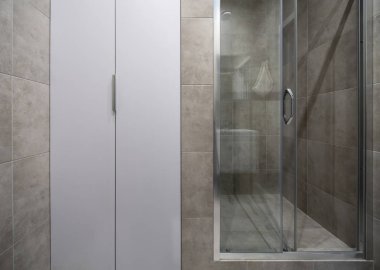 Duvarları büyük aydınlık banyo gri ile modern tarzda döşenmiş