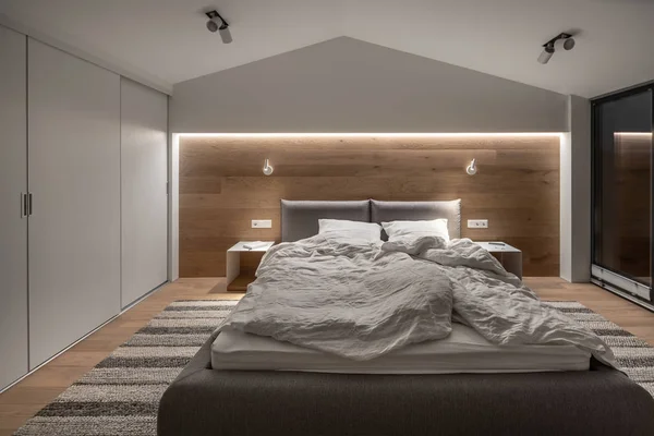 Стильная спальня в современном стиле с светлыми стенами и светящимися лампами — стоковое фото
