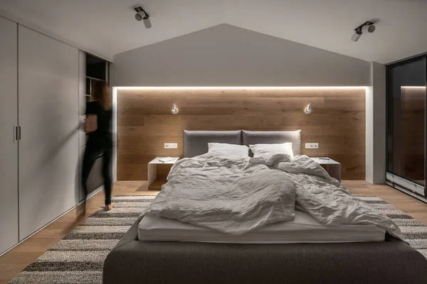 Стильная спальня в современном стиле с светлыми стенами и светящимися лампами — стоковое фото