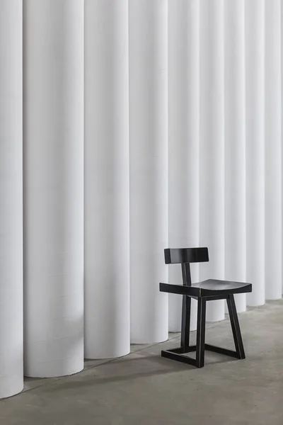 Czarne, drewniane krzesło na betonowej podłodze na tle białym teksturą kolumn — Zdjęcie stockowe