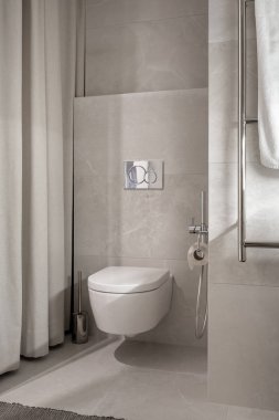 Işıklı modern banyo ile gri duvarlar ve zemin bir halı ile döşenmiş. Beyaz bir tuvalet, krom havlu askısı, duş perdeleri, fırça vardır. Dikey.