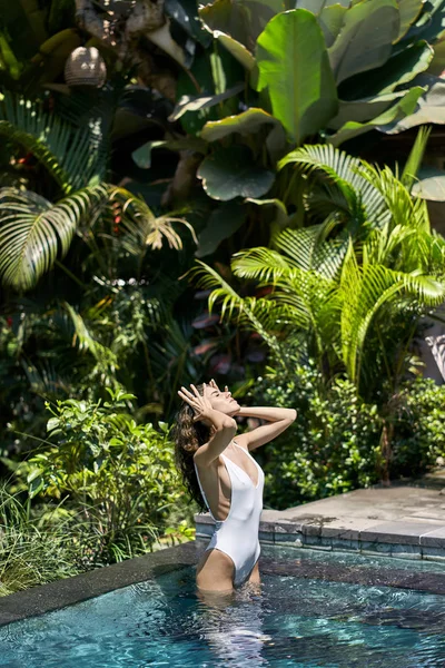 Bruna ragazza in costume da bagno in posa in piscina all'aperto su sfondo natura soleggiata — Foto Stock