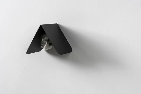 Modny czarny lampka metal na szarej ścianie w studio — Zdjęcie stockowe
