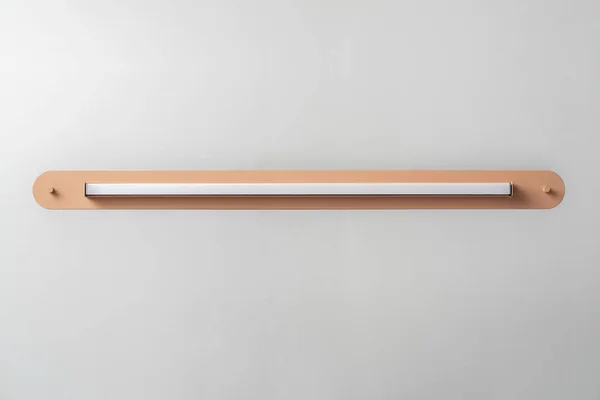 Oranžové kovová lampa na pozadí šedé zdi ve studiu — Stock fotografie