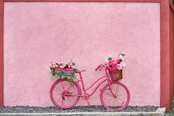 Ljusa rosa cykel med blommor i sina korgar utomhus — Stockfoto