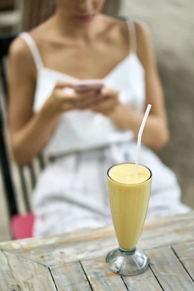 Žena používající její smartphone ve venkovní restauraci na tropické pláži — Stock fotografie