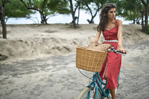 Morena mulher montando sua bicicleta na estrada rural no fundo da natureza tropical — Fotografia de Stock
