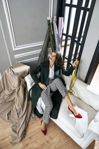 Модный дизайнер с измерительной лентой на светлом диване — стоковое фото