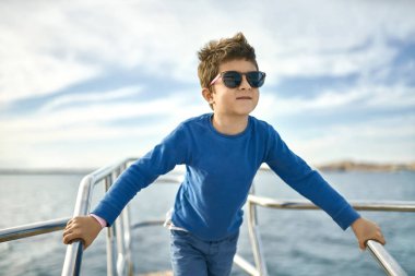 Neşeli küçük çocuk güneş gözlüğü yat güneşli deniz arka plan üzerinde poz