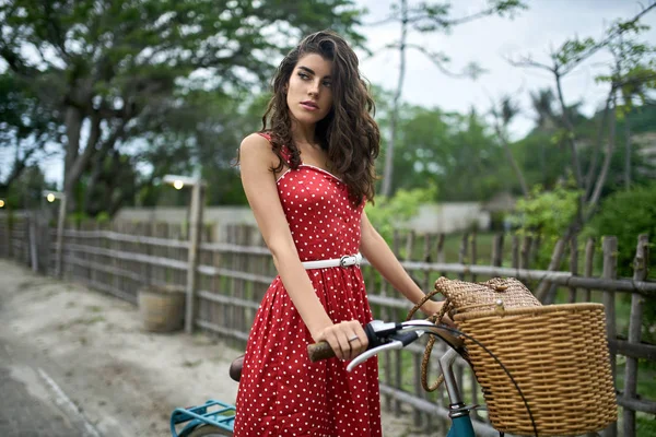 Mulher alegre posando com sua bicicleta na estrada rural no fundo da natureza tropical — Fotografia de Stock