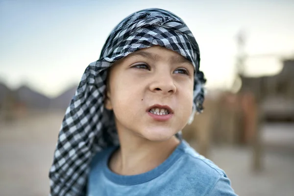 Small boy in checkered keffiyeh grimacing outdoors — Stock Photo, Image