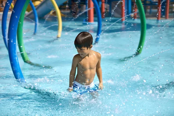 Menino pequeno posando na piscina com água azul em aquapark — Fotografia de Stock