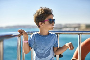 Küçük çocuk güneş gözlüğü yat güvertede lolipop yemek