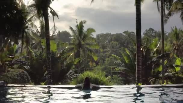 Nő a fehér fürdőruhát a szabadtéri medence zöld dzsungel háttér — Stock videók