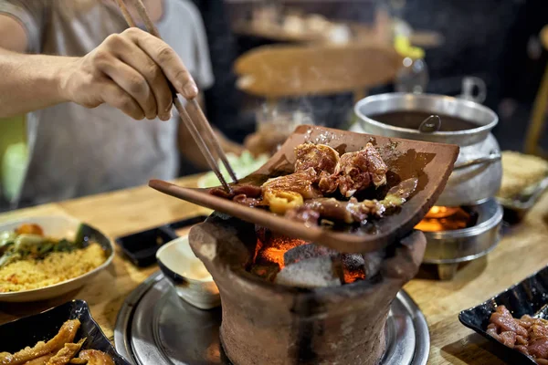 Visitor of traditional vietnamese restaurant cooking meat on hot pot — Stock Photo, Image