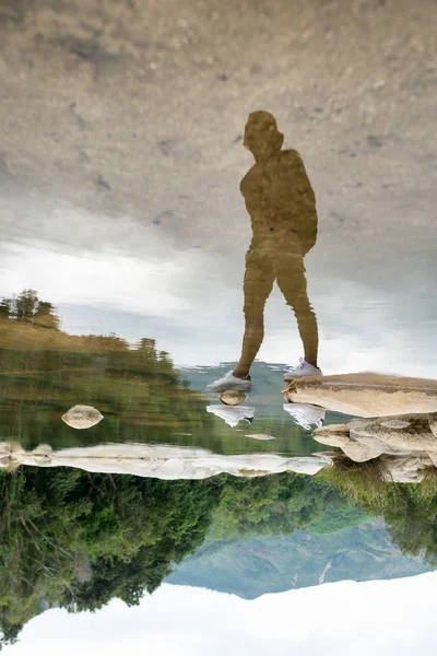 Invisible man in white sneakers reflected on water surface — Stock Photo, Image