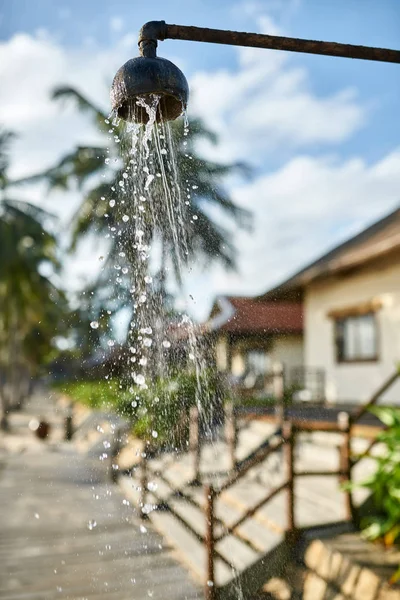 Doccia sulla spiaggia con acqua che scorre sul vecchio tubo di metallo — Foto Stock