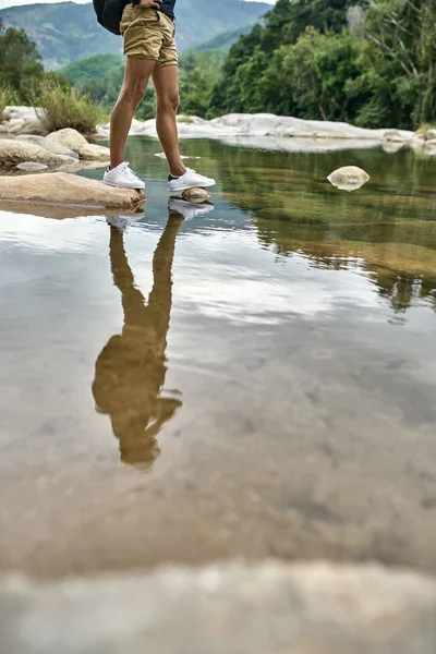 Traveler posing on seashore of shallow rocky river outdoors — Stock Photo, Image