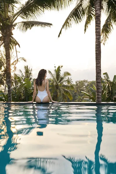 Mujer en traje de baño blanco en piscina al aire libre sobre fondo verde selva — Foto de Stock