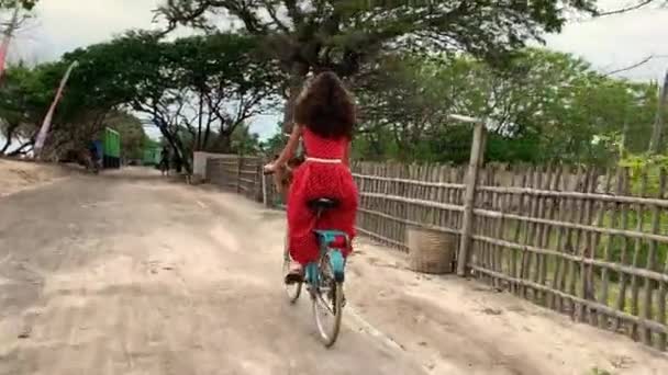 Frau mit Fahrrad auf Landstraße in tropischem Urlaubsort unterwegs — Stockvideo