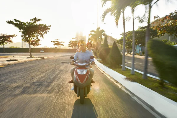 Parents with their little kid riding motorcycle on sunny city street