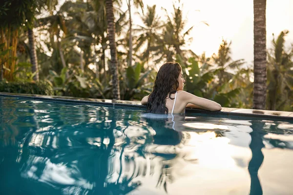 Mulher de maiô branco na piscina exterior no fundo verde da selva — Fotografia de Stock