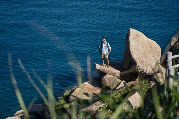 Traveler posing on stone on rocky seashore outdoors — Stock Photo, Image