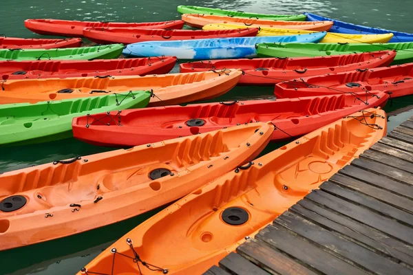 Multicolored canoes moored to wooden pier on nature background