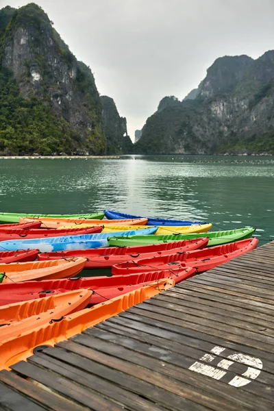 Veelkleurige kano's afgemeerd aan houten pier op natuur achtergrond — Stockfoto