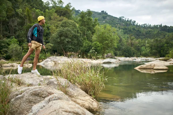 Путешественник позирует на берегу мелководной скалистой реки на открытом воздухе — стоковое фото