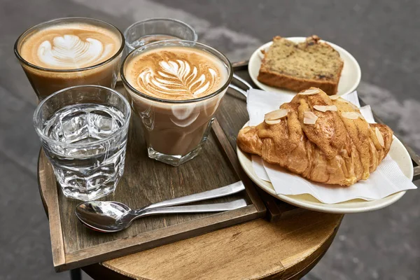 Milk coffee with croissant and bread and water on wooden table — Stock Photo, Image