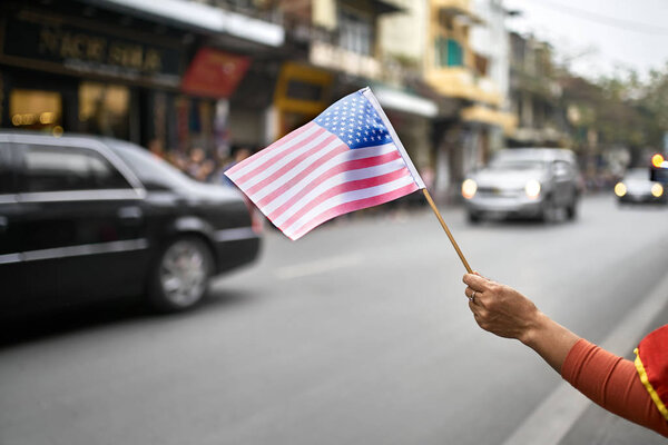 Гражданин с флагом приветствует проезд на автомобиле дипломатического сопровождения
