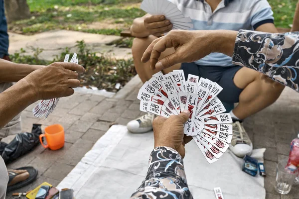 Asijští hráči, kteří hrají karty ve venkovním parku — Stock fotografie
