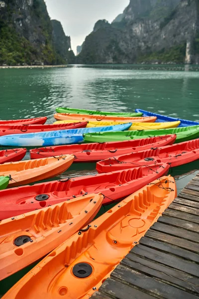 Canoas multicolores amarradas a muelle de madera sobre fondo natural —  Fotos de Stock