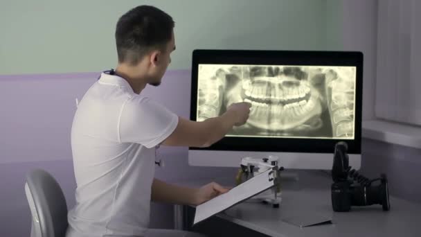 Dentist is examining results of orthopantomogram in his cabinet — Stock Video