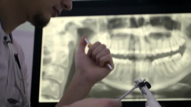 Дантист осматривает модель зубов гипсихиатра в своем кабинете — стоковое видео