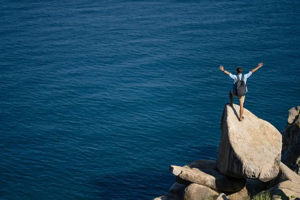 Traveler posing on stone on rocky seashore outdoors Stock Image