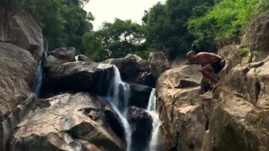 Vietnam'da şelale üzerinde kayalık uçurumdan atlama adam