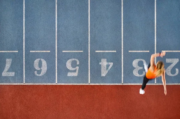 运动金发女子在五颜六色的体育场运行 — 图库照片