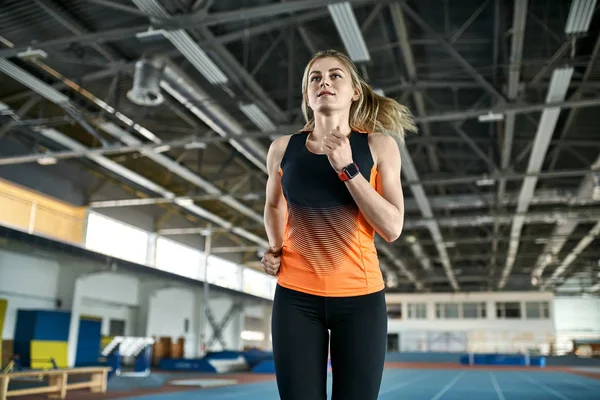 Mujer atlética rubia entrenando en el estadio interior — Foto de Stock