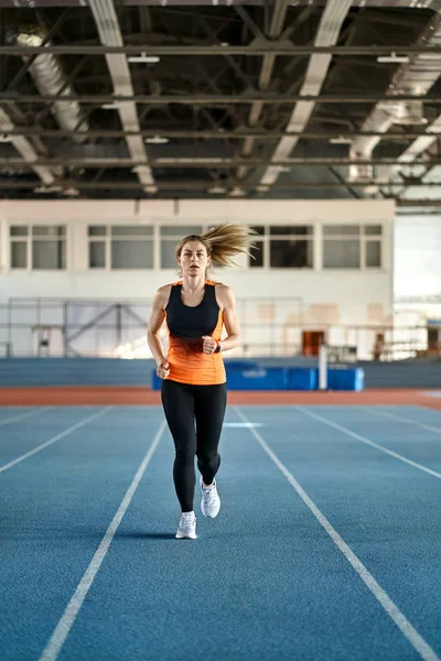 Mulher loira esportiva treinando no estádio indoor — Fotografia de Stock