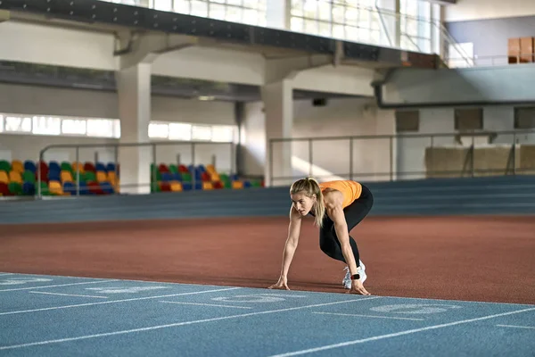 Блондинка-спортсменка тренируется на крытом стадионе — стоковое фото